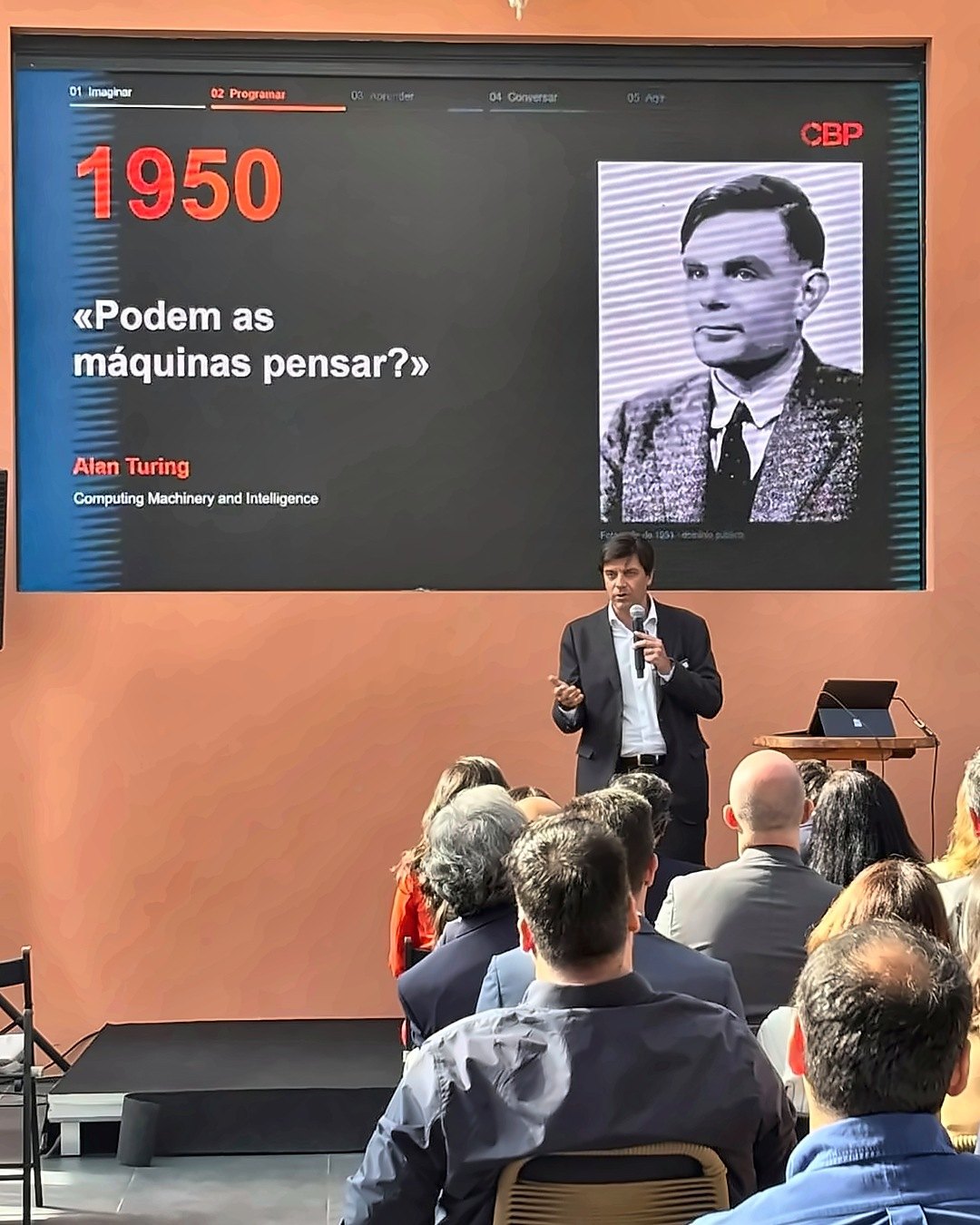 Miguel Sousa Soares em palco, diante de um ecrã com a pergunta de Alan Turing «Podem as máquinas pensar?»